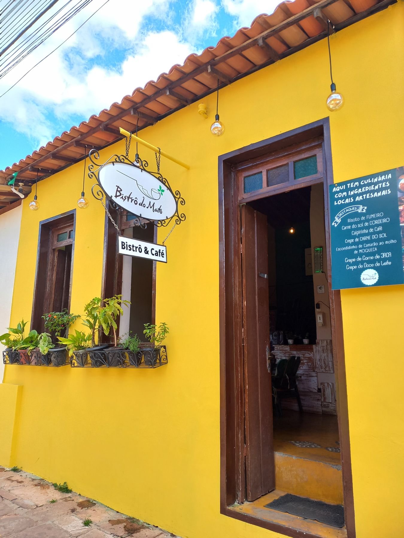 Fachada amarela do Bistrô do Mato, casa colonial com lâmpadas penduradas no centro histórico de Lençóis