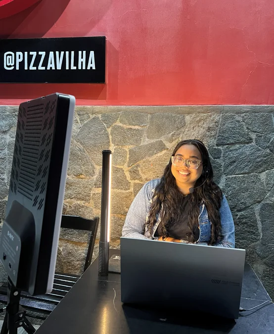 Camile Sampaio gravando conteúdo com notebook e iluminação na Pizza Vilha