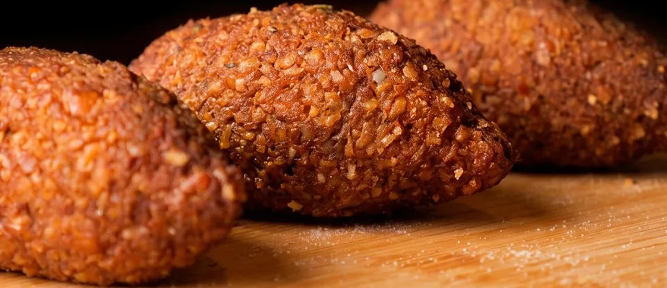 Kibes fritos dourados sobre tábua de madeira
